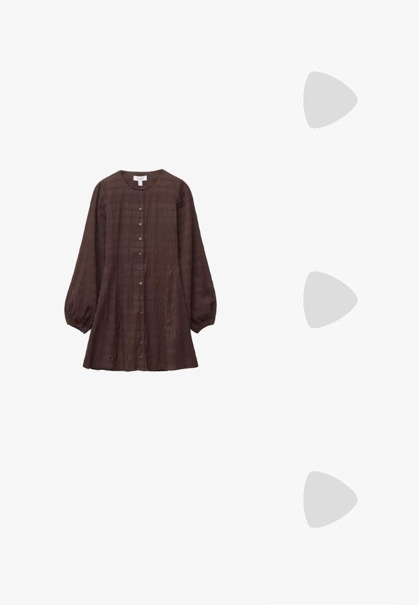 Brun, tekstureret bluse med knaplukning, rund halsudskæring og lange, puffede ærmer. Har vandrette mønstre og sidelommer.; Brune ruskinds slingback sko med spids tå og en slank hæl. Har en justerbar rem med en metalspænde.; Sort Michael Kors håndtaske med guldkæde, lynlåslukning og rundt gyldent MK-logo vedhæng på hvid baggrund.; Guldtonet metaløreringe med et cirkulært design, der har to kugler; en større og tekstureret kugle samt en mindre poleret kugle øverst.