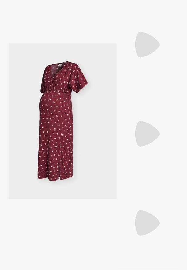 Donkerrode zwangerschapsjurk met wit bloemenpatroon, korte mouwen, V-hals, elastische taille en een zoom tot aan de enkel met een zijsplit.; Zwarte slingback schoen van lakleer met een lage blokhak, rustend op een gestructureerd blauw golvend tapijt en grijze, gewatteerde meubels.; Zwarte leren schoudertas met een glad oppervlak, afgeronde vorm en een dunne band. Voorzien van een ritssluiting en minimale metalen accenten.; Zilverkleurige stervormige oorringen met een gladde, gepolijste afwerking op een effen witte achtergrond.