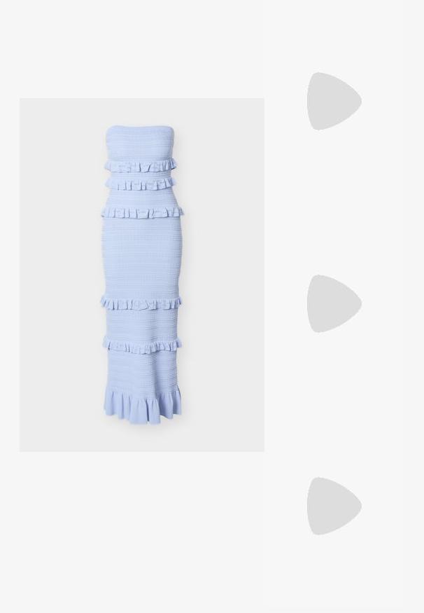 Lichtblauwe strapless midi-jurk met getextureerde horizontale strepen en meerdere gerimpelde lagen over het lijfje, de taille en de zoom.; Bruine leren cowboylaarzen met puntige neuzen, decoratieve stiksels en zijfranje, voorzien van een gestapelde hak voor extra hoogte.; Bruine suède schoudertas met een brede schouderband, voorzien van goudkleurige metalen studs die in een verticale patroon op de voorkant en zijkanten zijn gerangschikt.; Een paar glanzende zilveren oorbellen in de vorm van een zeester met vijf onregelmatige armen op een witte achtergrond.