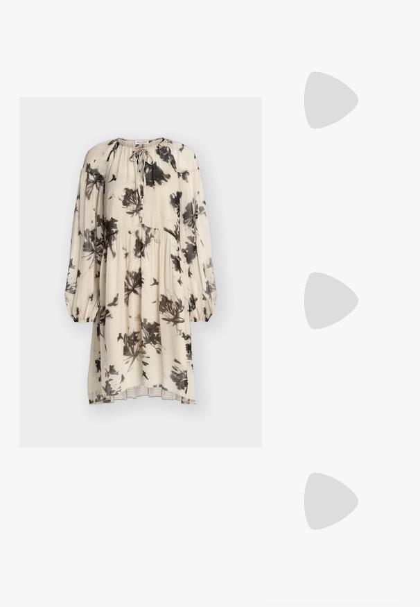 Robe crème à manches longues avec imprimé floral et oiseaux noirs, taille froncée, poignets élastiques et détail noué au col.; Chaussure noire à talons hauts équilibrée sur son talon sur un comptoir réfléchissant près de porte-dossiers métalliques avec des dossiers blancs.; Sac à main en cuir noir avec poignée chaîne dorée et pendentif circulaire avec logo MK, petit texte "Michael Kors" centré près du bas.; Bracelet en métal doré en forme de manchette avec un détail floral à une extrémité et une perle blanche ronde à l'autre. Le design est épuré et minimaliste.