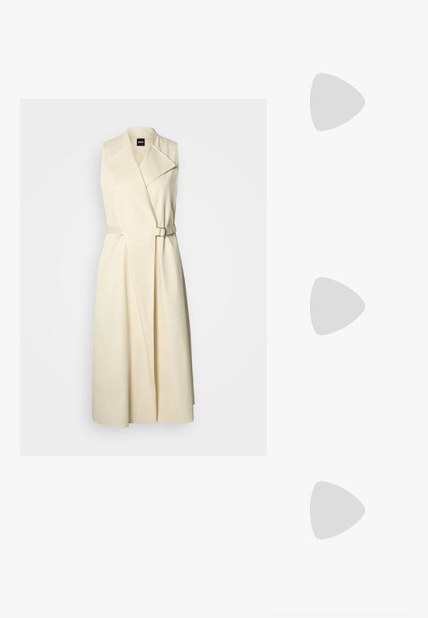 Trench-coat long beige sans manches avec de larges revers et une ceinture assortie avec boucle autour de la taille.; Botte noire en cuir jusqu'au genou avec bout pointu et petit talon kitten sur un fond clair uni.; Sac à bandoulière en cuir noir de forme rectangulaire incurvée, avec une chaîne dorée tissée dans la bandoulière noire tressée et une fermeture éclair sur le dessus.; Boucles d'oreilles en résine noire avec une finition brillante et des accents en métal argenté. Forme circulaire avec une découpe et une fermeture à tige.