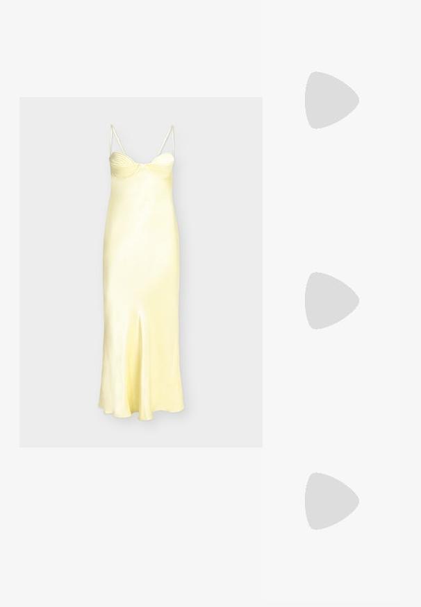 Robe nuisette en satin jaune avec bonnets à armatures, détail froncé au niveau de la poitrine, fines bretelles spaghetti et fente centrale à l'avant.; Sandale à talons hauts argentée présentant plusieurs brides croisées, une bride de cheville avec boucle, et un talon sculpté, le tout avec une finition métallique brillante.; Pochette texturée noir et blanc de forme arrondie, avec une chaîne en métal argenté et un fermoir en métal en haut.; Boucles d'oreilles en métal argenté avec un design ondulé et sculptural, présentant une finition polie et des formes irrégulières, mettant en valeur une esthétique contemporaine.