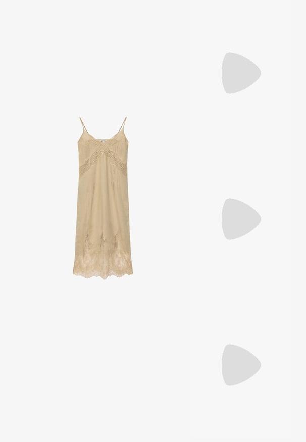 Robe nuisette beige avec fines bretelles, bordure en dentelle le long du décolleté, détail en dentelle croisée sur la poitrine et ourlet en dentelle.; Sandale à talon marron Calvin Klein suspendue au-dessus d'un sol extérieur en dalles de bois et gravier avec un arrière-plan flou de verdure et de pierres.; Sac à épaule en cuir noir, de forme courbée, avec une texture douce et une seule sangle; il comporte une fermeture éclair dorée et un logo discret.; Boucles d'oreilles en métal doré présentant un design circulaire avec deux sphères, l'une plus grande et texturée, et une petite boule polie en haut.