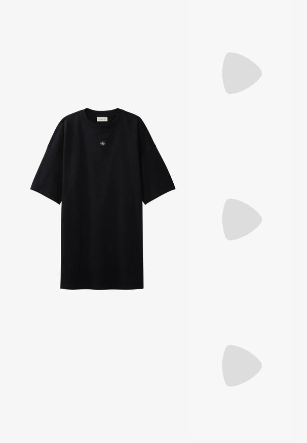 Μαύρο oversize T-shirt με κοντά μανίκια και μικρό ταμπελάκι με το λογότυπο Calvin Klein, τοποθετημένο στο κέντρο κάτω από το ντεκολτέ.; Μαύρο δερμάτινο σανδάλι Calvin Klein με λουράκι στον αστράγαλο και αγκράφα να αιωρείται πάνω από ξύλινο και πέτρινο πλακάκι σε εξωτερικό χώρο.; Ορθογώνια γυαλιά ηλίου ανοιχτού ροδακινί χρώματος με χοντρές σκελετούς και ταιριαστά σκουρόχρωμα φακούς σε απλό, φωτεινό φόντο.; Μαύρη δερμάτινη τσάντα ώμου με μακρύ λουράκι, πλαϊνές θήκες και ανάγλυφο λογότυπο Calvin Klein στο μπροστινό μέρος.