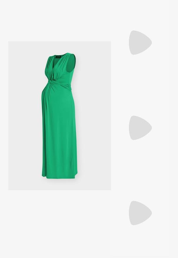 Robe de maternité longue verte sans manches avec un détail de tissu froncé au niveau de la poitrine et de la taille sur un fond uni.; Sandales à talons en cuir noir avec une large lanière sur le bout des orteils et une boucle sur la lanière de la cheville. Talon rectangulaire épais.; Sac fourre-tout noir en simili cuir avec une finition texturée, deux longues poignées et des accents en métal doré sur le côté. Shape rectangulaire.; Collier délicat à double chaîne en or avec de petites perles blanches espacées régulièrement sur un fond clair uni.