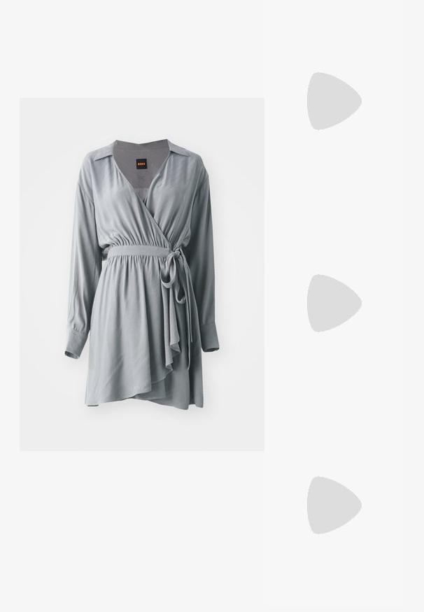 Vestido envolvente gris hecho de una tela suave, con mangas largas, una cintura ceñida y un dobladillo asimétrico fluido. Incluye cuello y un cinturón de lazo.; Salón de ante negro con punta puntiaguda, tacón de aguja delgado de altura media y diseño de corte bajo sobre un fondo liso.; Bolso de hombro de cuero negro con una forma estructurada, que presenta un logo dorado "DKNY" en el frente y una correa corta y ajustable.; Pendientes de aro de plata con un acabado pulido y la marca DKNY, exhibidos sobre un fondo blanco liso.