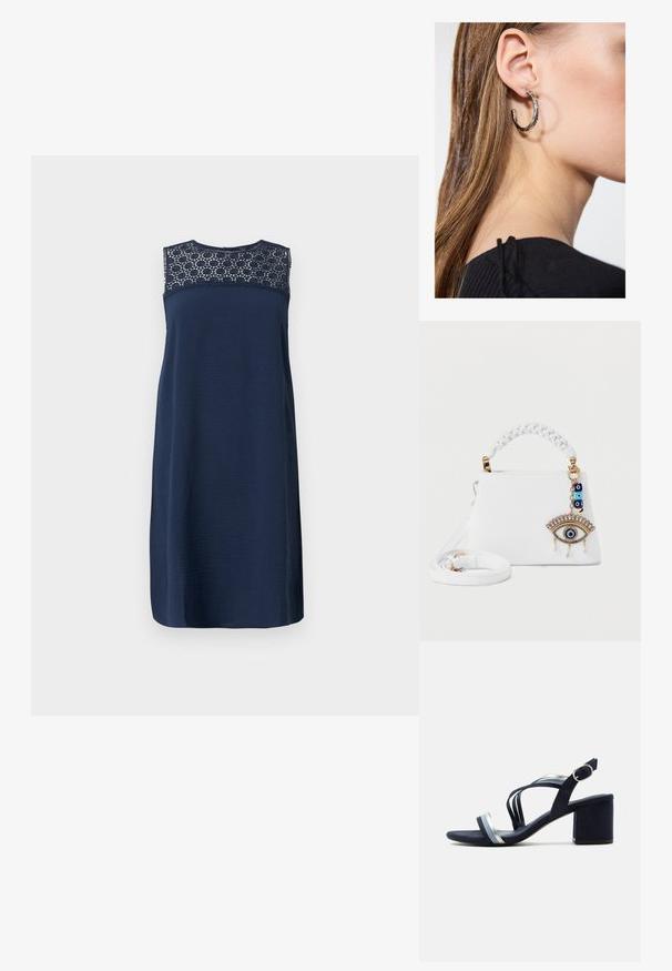 Vestido sin mangas azul marino con un cuerpo texturizado y detalles de encaje en el escote. Diseño de corte recto, de longitud a la rodilla y con un acabado suave.; Sandalia azul marino con tacón, con tiras plateadas y azul claro, hebilla en el tobillo y tacón grueso sobre fondo blanco.; Bolso blanco con asa trenzada y correa desmontable, con un charm en forma de ojo dorado y azul con cuentas y perlas colgantes.; Pendiente de aro de plata con un acabado pulido, que presenta pequeños detalles en dorado y una forma redonda, llevado en el lóbulo.
