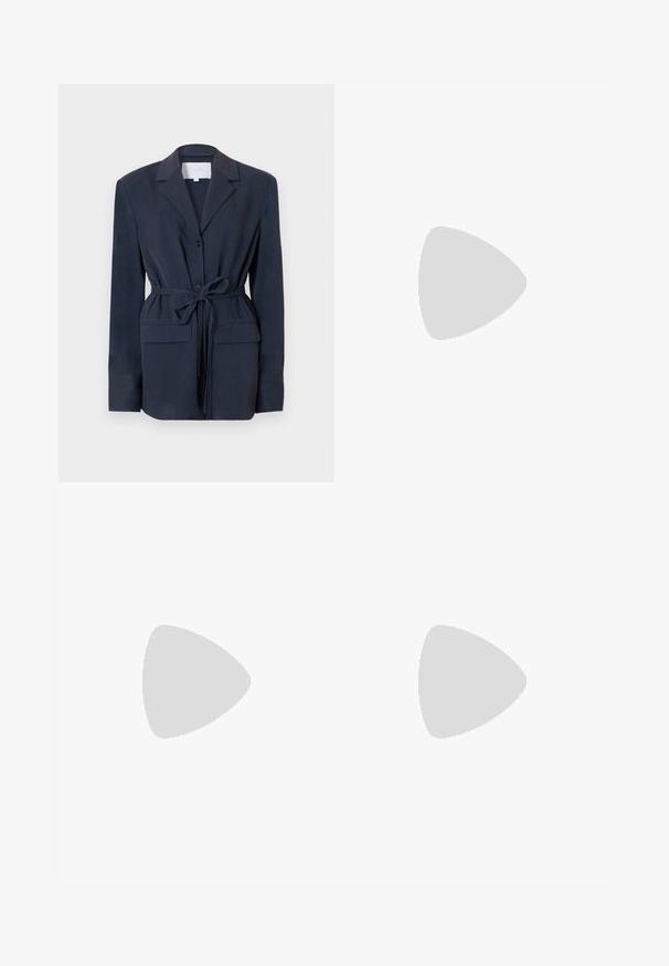 Blazer bleu marine en tissu lisse, avec col cranté, fermeture à un bouton, deux poches avant et ceinture à la taille pour ajustement.; T-shirt bleu clair à manches courtes et col rond, présenté à plat sans logos ni motifs visibles sur un fond blanc uni.; Pantalon bleu marine à jambes droites avec passants de ceinture, fermeture éclair à l'avant et taille propre sur un fond clair.; Chaussure plate slingback en beige clair avec une tige en maille, un bout pointu et un petit talon. Dotée d'une sangle ajustable pour un bon maintien.