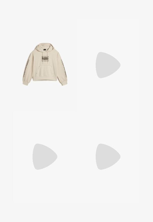Beige forkortet hættetrøje med snorhætte, frontlomme og intrikate sorte mønstre på brystet og ned ad ærmerne. Blødt stof.; Sort bomulds t-shirt med rund halsudskæring og korte ærmer. Har en frontlomme med et rødt hjerte-logo og hvid tekst.; Leopardprint bukser lavet af blødt stof, med en afslappet pasform, vide ben og en elastisk talje i beige og brune nuancer.; Benen krydset iført beige Puma-sneakers med leopardstriber og flæset cremefarvede sokker på et blåt tæppebelagt gulv.