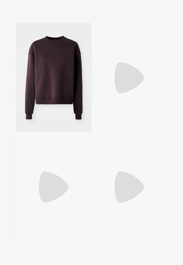 Mørkebrun sweatshirt i en blød bomuldsblanding med rund hals, lange ærmer og ribbede kanter og kant for et tætsiddende udseende.; Brune straight-leg denim jeans med forlommer, møntlomme, bæltestropper og dobbelte knapper i taljen.; Fødder iført beige vævede Adidas sneakers med gummisåler og hvide ankelsokker på en grøn struktureret gulv.; Brun lakeret håndtaske med rektangulær form, to lange håndtag og subtile buede detaljer på fronten.