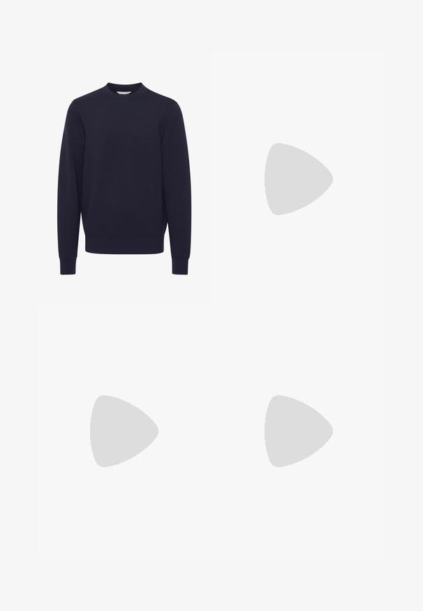 Tumedat sinine sviiter, mis on valmistatud pehmest kangast. Omab ümarat kaelust, pikki varrukaid ning soonikkoes ääri ja hemmi. Sile tekstuur, minimalism disain.; Roheline, pruun ja beež kamuflaažipritsaka pikade varrukatega T-särk, ümmarguse kaelusega. Omab segatud mustrit ebaregulaarsest täppidest ja tekstuuridest.; Mustad mustad püksid, millel on lõdvestatud istuvus, küljetaskud, volditud esiosaga disain, reguleeritavad pahkluuseotud sneetid ning valmistatud vastupidavast kangast.; Tumepruun nahast loafer paksu musta kummipõhjaga, eksponeeritud beeži vaiba ja diivani taustal.