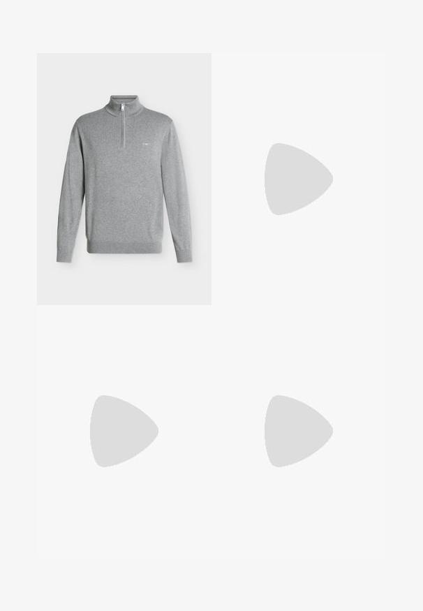 Helehall pikkade varrukatega pullover, millel on poollukuga krae ja väike tikitud embleem vasakul rinnal.; Helehall sinine pika varrukaga nööpidega särk, nööpidega krae ja vasakul rinnataskuga.; Tumed roheline püksid sirge sääre disainiga, valmistatud siledast kangast. Omab lamedat esipaneeli ja standardset vöökohta, millel on vööloopide jaoks augud.; Mustast nahast brogue-tüüp king paksu tallaga, hõljumas beežil vaibal, ümmargune puidust laud, kus on raamatud virnas ja hele värvi diivan taustal.