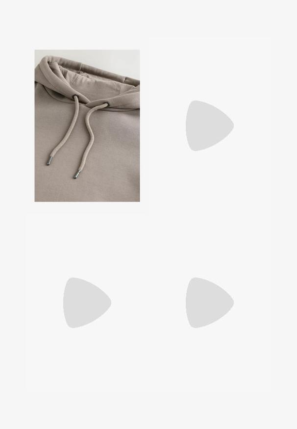 Beige hoodie met een zachte textuur, voorzien van een capuchon met trekkoord en metalen uiteinden, en een comfortabele pasvorm, gemaakt van een katoenmengsel.; Beige katoenen t-shirt met een ronde hals, korte mouwen en de tekst "STUDIO EDITION" in zwarte print over de borst.; Lichtbeige, relaxed-fit broek met een elastische tailleband, koordsluiting en patchzakken, gemaakt van ademend materiaal en met een matte afwerking.; Witte lage sneaker met beige suède accenten, veterluiting en dikke witte zool, weergegeven vanaf de buitenkant op een witte achtergrond.