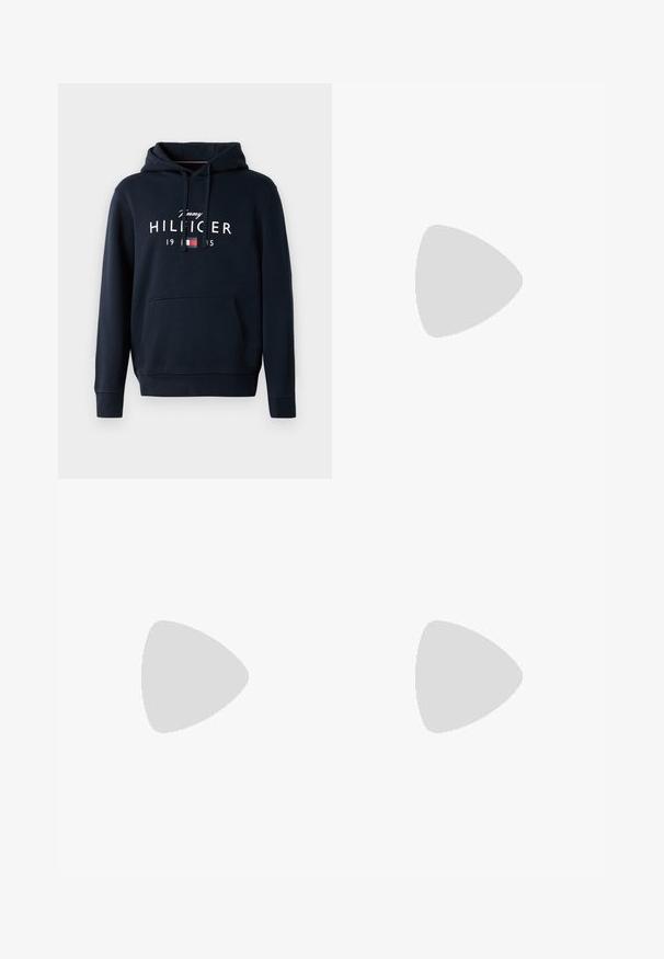 Sweat à capuche bleu marine en tissu doux, avec une poche kangourou, une capuche à cordon et un logo en texte blanc avec des accents rouges et bleus.; Polo shirt à manches courtes bleu clair en coton, avec une patte de boutonnage à deux boutons et un petit logo brodé sur la poitrine gauche.; Pantalons noirs ajustés en coton ; ils présentent un devant plat, des coutures visibles, et une coupe droite. Fermeture par bouton à la taille.; Jeune homme en veste en cuir foncée et jean, assis sur un tabouret en bois, penché en avant, les bras croisés, regardant sur le côté sur fond blanc.