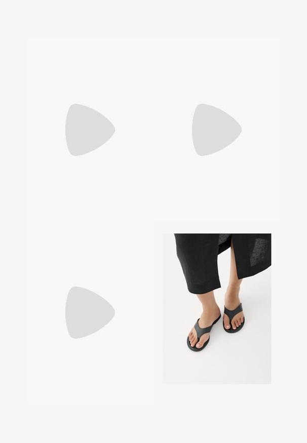 Combinaison marron sans bretelles avec corsage ajusté et pantalons larges, drapés et plissés créant une silhouette fluide.; Gros plan sur des pieds portant des sandales en cuir noire de type tongs, avec l'ourlet d'une jupe noire visible au-dessus des chevilles, sur un sol blanc.; Lunettes de soleil rondes teinte brun avec une monture bordeaux brillante. Branches fines avec un détail de marque subtil. Design de verres plats.; Petit sac à main noir brillant avec deux longues anses et des détails à cordon sur les côtés sur un fond clair uni.