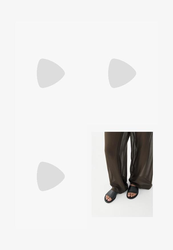 Schwarzer und cremefarbener gemusterter Jumpsuit mit kurzen Ärmeln, V-Ausschnitt und elastischem Bund. Der Stoff wirkt leicht und hat ein fließendes Design.; Füße in schwarzen Slide-Sandalen kombiniert mit lockeren, durchscheinenden braunen Hosen vor einem schlichten weißen Hintergrund.; Schwarze rechteckige Brille mit klaren Gläsern, abgerundeten Kanten und seitlichen Akzenten, mit glänzender Oberfläche des Rahmens und der Bügel.; Kleine schwarze glänzende Handtasche mit zwei langen Griffen und seitlichen Kordelzug-Details vor einfachem hellem Hintergrund.