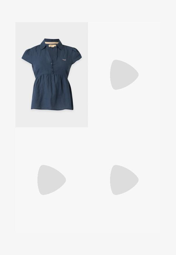 Blusa azul marino de mujer con mangas cortas, cuello, tres botones en la parte delantera y un pequeño logo bordado en el pecho.; Vaqueros beige de pierna ancha con cinco bolsillos y costuras visibles en las rodillas, mostrados extendidos sobre un fondo liso gris claro.; Sandalias de cuero marrón con dos correas anchas, una correa trasera con un hebilla de metal y una suela de goma gruesa con un patrón texturizado.; Bolso hobo de ante marrón con una gran apertura curvada y una amplia correa para el hombro. Presenta una costura centrada en la parte frontal. Textura suave.