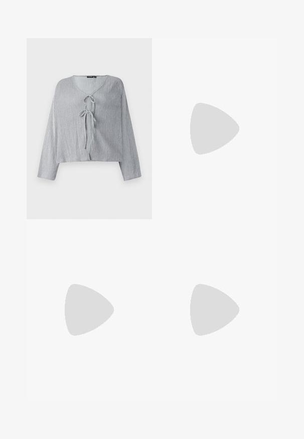 Blouse courte gris clair avec des manches longues, encolure en V et fermeture par lien à l'avant. Le tissu texturé présente des lignes verticales subtiles.; Jupe en denim gris foncé avec des ornements en clous argentés. Présente une coupe ajustée, un design classique à cinq poches et des passants de ceinture.; Bottes noires à la cheville avec un talon épais, ornées de clous argentés et de sangles, en cuir avec une texture lisse et une fermeture éclair.; Petit sac à main noir brillant avec deux longues anses et des détails à cordon sur les côtés sur un fond clair uni.