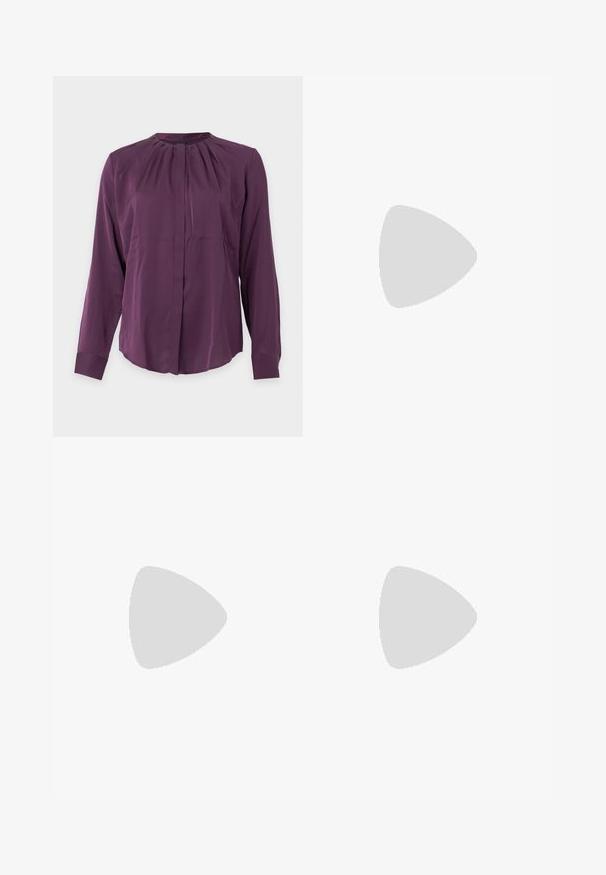 Lilla bluse med lange ærmer, rund halsudskæring, plisseret detalje nær kraven og skjulte knapper foran.; Mørkegrøn omslagsnederdel lavet af glat stof, med en asymmetrisk nederkant og et sømløst taljebånd for et rent design.; Sort læder slingback sko med spids tå, tre sølvspænder på forsiden og lav lille hæl på hvid baggrund.; Sort spandtaske i krokodillepræget læder med enkelt skulderrem og lille sølvfarvet mærkelogo foran nederst i midten.