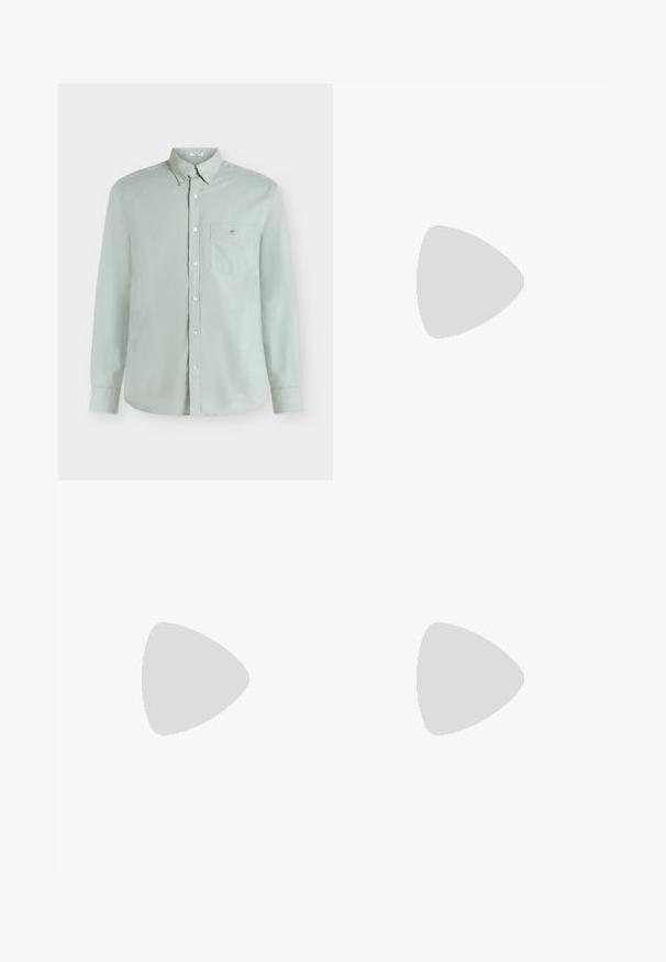 Chemise vert clair à manches longues avec boutons, poche poitrine et petit logo brodé, présentée sur fond blanc uni.; Pantalon slim noir avec passants de ceinture, bouton devant et fermeture éclair, présenté à plat sur un fond gris clair.; Mocassin en cuir noir présenté en lévitation au-dessus d'un tapis beige avec un canapé beige en arrière-plan.; Ceinture en cuir noir roulée avec une boucle métallique argentée rectangulaire sur un fond clair uni.