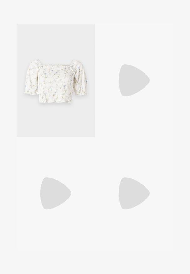 Blouse florale blanche avec des manches bouffantes courtes, un corsage froncé et de délicats motifs de fleurs bleues et jaunes.; Jupe longue à volants en tissu crème avec des bords ondulés noirs. Dotée d'une taille élastique pour plus de confort et d'un tomber fluide et léger.; Jambes portant des leggings côtelés foncés associés à des ballerines noires avec de petits détails en nœud sur fond blanc.; Sac à main rectangulaire tissé beige avec une sangle en cuir marron clair ornée de nœuds et une fermeture à crochet dorée sur un fond uni.