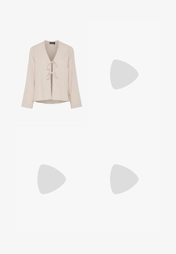 Blouse beige clair avec un décolleté en V profond, des manches longues et une fermeture à nouer à l'avant. Fabriquée en tissu texturé et doux avec une coupe décontractée.; Short en denim blanc taille haute avec poches avant et ceinture en tissu nouée en nœud à la taille.; Baskets basses avec une base blanche et un motif de cuir de vache brun foncé, semelle beige, et logo de marque doré subtil sur le côté.; Sac à main en imitation serpent marron avec une surface texturée, un design arrondi, une bandoulière unique et une poche zippée à l'avant.