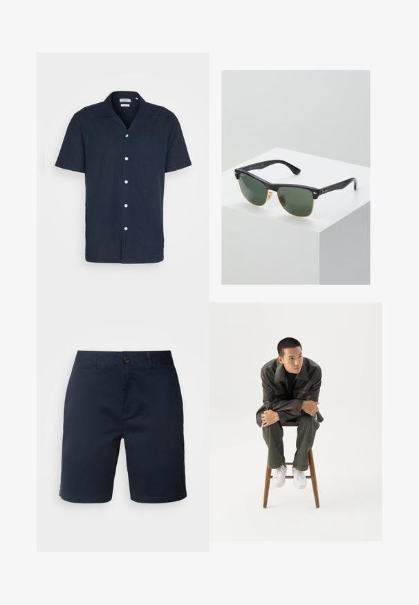 Kurzärmliges Marineblaues Hemd mit Knöpfen aus leichtem Stoff, mit Kragen, sechs weißen Knöpfen und einem entspannten Schnitt.; Marineblaue Shorts aus Baumwolle, mit einem Knopf- und Reißverschlussverschluss, flachem Bund und seitlichen Taschen mit einer glatten Textur.; Junger Mann in dunkler Lederjacke und Jeans sitzt auf einem Holzstuhl, lehnt sich mit verschränkten Armen nach vorne und schaut seitlich vor weißem Hintergrund.; Ray-Ban Sonnenbrillen mit grünen Gläsern, schwarzen Kunststoffrahmen und goldenen Akzenten an den Rändern. Quadratische Form mit matter Oberfläche.