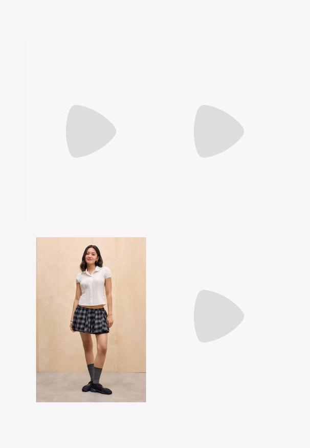 T-shirt noir à manches courtes en coton. Il possède un col rond et un ourlet droit. Design minimaliste sans motifs ni accents.; Jeune femme se tenant à l'intérieur, portant un blouse blanche à manches courtes, une jupe à carreaux noire et grise, des chaussettes grises et des baskets noires.; Bottines en cuir noir avec un bout pointu, un petit talon carré et un détail de couture. Elles sont dotées de panneaux élastiques sur les côtés pour un enfilage facile.; Deux sacs en daim beige Juicy Couture, l'un un petit porte-poignet avec logo, l'autre un sac à bandoulière avec le texte "Juicy" en strass.