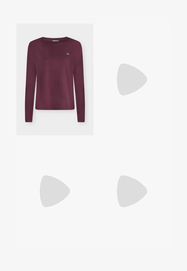 Langærmet crewneck-shirt i dyb bordeaux med lille hvidt broderet logo på venstre bryst.; Sorte skinny jeans lavet af denim med en glat tekstur. Har en frontlukning med knap og lynlås, fem lommer og en slank pasform.; Sort læder snørestøvle med kraftig sål hængende over et træbord udendørs med grøn løvbaggrund.; Brun ruskind skuldertaske med flettet kvastdetalje på frontklappen og justerbar skulderrem.