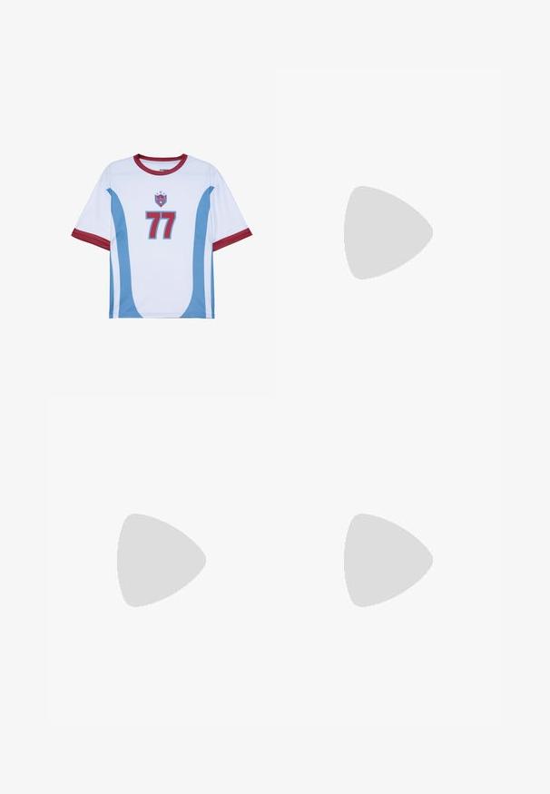 Maillot de football à manches courtes en blanc avec des accents rouges. Présente des rayures courbées bleues et le numéro "77" en bleu. Dispose d'un col rond.; PROHIBITED Short - red cream; Baskets en daim noir avec accents blancs, arborant un logo doré. Portées avec un jean en denim bleu clair et posées sur une surface bleue texturée.; Collier avec des perles noires et multicolores alternées, comportant de petits anneaux en argent et un pendentif rectangulaire en perle transparente.