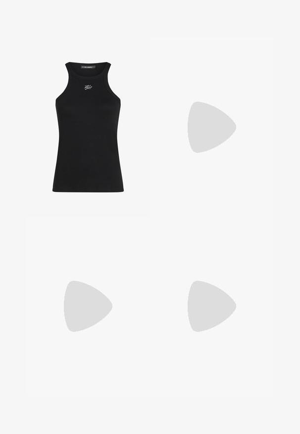 Débardeur noir à côtes avec un col rond et des bretelles étroites. Possède un petit logo blanc sur la poitrine.; Shorts en denim bleu arrivant aux genoux avec un ourlet retroussé, cinq poches et une fermeture à bouton en métal. Le tissu présente une apparence légèrement délavée.; Sabot noir Crocs avec trous de ventilation et bride flottant au-dessus d'un tapis beige tissé, table basse en bois avec des livres, et canapé beige en arrière-plan.; Sac de courses réutilisable avec motif floral rose et rouge, posé debout sur un fond uni clair.