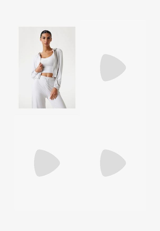 Biele športové oblečenie obsahujúce mikinu na zips a priliehavý tielko. Mäkkučký materiál, voľný strih, s pásom na šnurovanie a jednoduchým logom.; Biely croptop vyrobený z hladkej bavlny, s vysokým výstrihom a krátkymi rukávmi. Malé vyšívané logo v dolnom rohu.; Zelené legíny s vysokým pásom vyrobené z elastického materiálu. Majú hladkú textúru a rozšírený lem na spodnej časti.; Biele tenisky s materiálom z mlátenice, gumovou podrážkou, bezšnúrovým dizajnom s elastickými pásikmi a pozlátenými akcentmi.