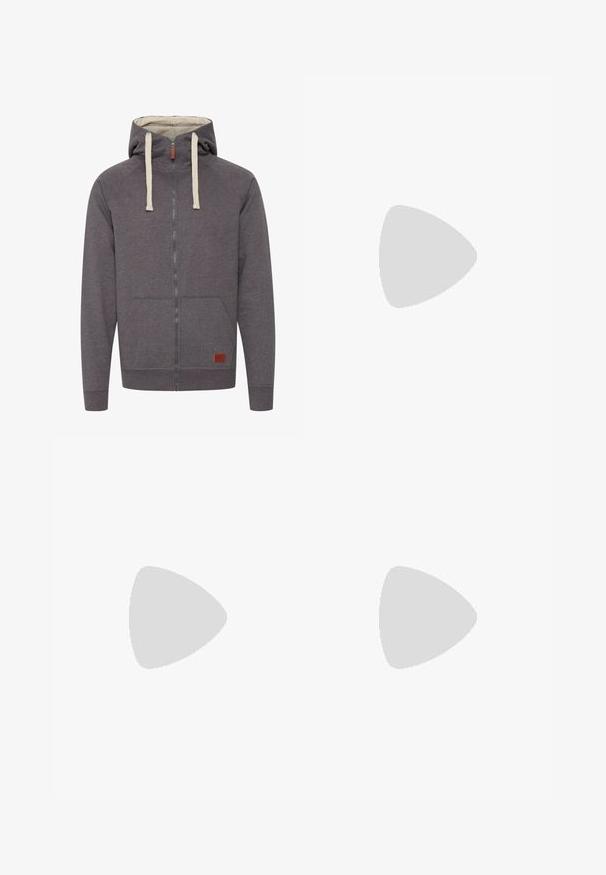 Szürke, cipzáros kapucnis pulóver, húzózsinórral, kenguru zsebekkel és bordás mandzsettával. Az elején egy kis márkázott bőrcímke található.; Fehér pamut póló, rövid ujjakkal és kerek nyakkivágással. Jellemzője egy kis, diszkrét Nike logó a mellkason és egy oldalsó címke.; Beige, könnyű nadrág, rugalmas derékkal és zsinórral. Ráncokkal és laza szabással rendelkezik, puha, sima anyagból készült.; Fehér bőr sportcipők zöld Nike logóval, kerek orral, lapos talppal, világoskék farmernadrággal párosítva, kék szőnyegen bemutatva.