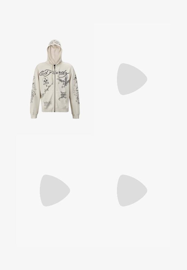 Sudadera beige con cremallera y capucha. Presenta diseños gráficos en negro, incluyendo texto e ilustraciones de una calavera y un águila. Dos bolsillos frontales.; Camiseta de algodón negra con mangas cortas, cuello redondo y un pequeño logo amarillo en el área del pecho izquierdo. Diseño simple y ajuste regular.; Vaqueros de pierna ancha en azul oscuro con un gran gráfico de un perro de caricatura blanco en el bolsillo trasero. Textura de denim, diseño tradicional de cinco bolsillos.; Zapatillas de ante negras con suelas de goma blancas y rayas laterales, combinadas con pantalones cargo verde claro, de pie sobre una superficie oscura texturizada.