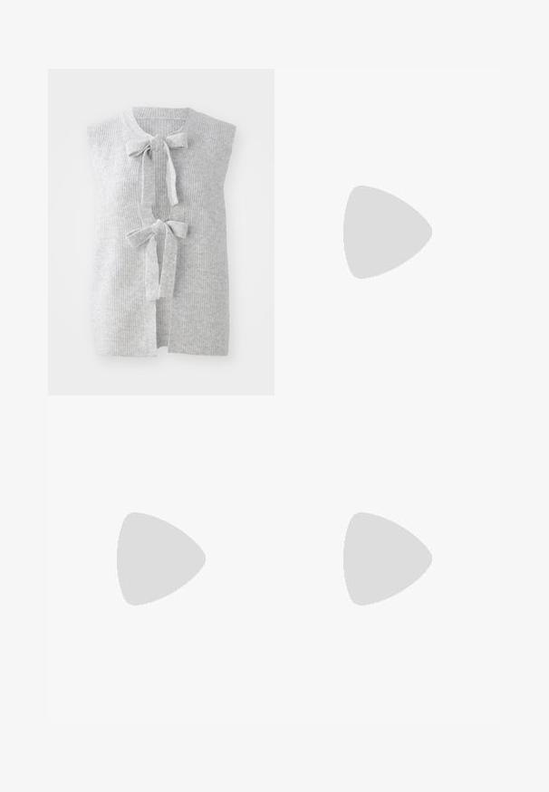 Graue, ärmellose Strickweste mit gerippter Textur und zwei vorderen Schleifen. Offenes Frontdesign aus einem weichen, leichten Material.; Weißes Kurzarmoberteil mit Rundhalsausschnitt. Verfügt über geraffte Textur an den Seiten und eine figurbetonte Silhouette, gefertigt aus weichem, dehnbarem Material.; Weiße weit geschnittene Hose aus leichtem Stoff. Mit einem elastischen Bund und Kordelzug sowie Seitentaschen. Glatte Textur.; Hellrosa Wildleder-Sneaker mit weißen Streifen und Schnürsenkeln, ausgestattet mit einer strukturierten Zunge und einer Gummisohle, auf einem blauen Teppich platziert.