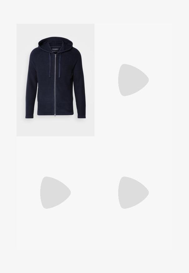 Felpa con zip di colore blu navy, realizzata in maglia testurizzata, con maniche raglan, cappuccio regolabile con lacci e chiusura frontale con zip.; T-shirt in cotone navy con maniche corte, scollatura rotonda e un piccolo logo bianco che rappresenta un globo con testo nella zona sinistra del petto.; Pantaloni in cotone beige con un design a gamba dritta, caratterizzati da una chiusura con bottone, cinque tasche e dettagli di cucitura discreti. Texture liscia.; Sneakers bianchi dalla texture liscia, con dettagli in pelle marrone e particolari neri, abbinati a pantaloni neri su misura. Sfondo in parquet.
