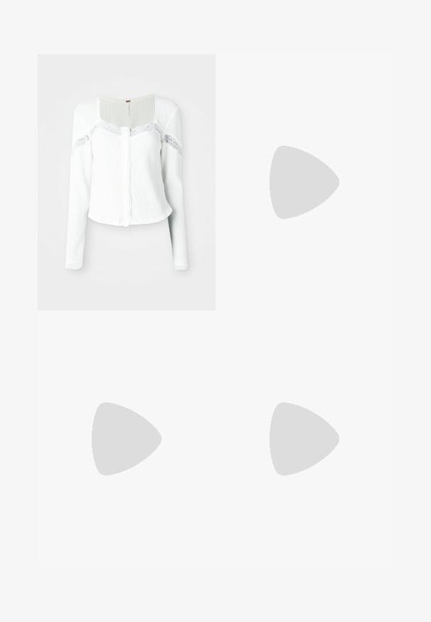 Balts garas piedurknes kardigāns, izgatavots no teksturēta auduma, ar mežģīņu akcentiem uz pleciem un pogu priekšpusi.; Balta un melna sporta krekls ar gariem mežģīņu piedurknēm, ar melnu grafisko izdruku, kurā rakstīts "Fly Tanzbar", un Adidas logotipu.; Baltas sporta bikses ar brīvu piegriezumu, elastīgu jostu un melnām sānu svītrām. Aprīkotas ar rāvējslēdzēja kabatām un elastīgām aprocēm pie potītēm.; Balti kedai ar brūniem svītrām, valkāti ar brūniem biksēm uz zila paklāja grīdas.