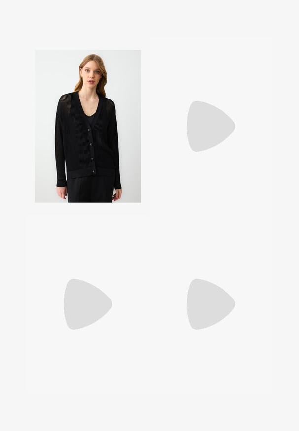 Donna con capelli castano chiaro che indossa un cardigan nero strutturato con bottoni sopra una maglietta nera, in piedi contro uno sfondo leggero e uniforme.; T-shirt in cotone nero con vestibilità rilassata, maniche corte, scollatura arrotondata e una texture liscia. Nessuna trama o accento visibile.; Pantaloni neri a gamba larga con pieghe, caratterizzati da una texture liscia e un design a vita alta. Stile minimalista, senza hardware o decorazioni visibili.; Décolleté in vernice nera con punta affusolata e tacco in geometria cubica. Presentano un design elegante e minimalista, con una texture liscia.; Borsa a tracolla nera in pelle con una forma curva, manico rimovibile e accessori dorati. La borsa presenta una patta con un dettaglio a fibbia.