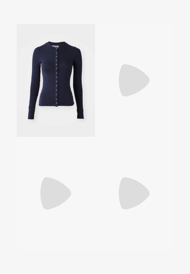 Marineblaue langärmelige Strickjacke mit Rundhalsausschnitt, taillierter Form und vorderem Knopfverschluss mit metallischen Akzenten. Weicher, strukturierter Stoff.; Weißes kurzärmliges T-Shirt aus weicher Baumwolle, mit Rundhalsausschnitt und figurbetonter Form. Keine sichtbaren Muster oder Verzierungen.; Hellgraue Sweatpants mit entspannter Passform, elastischem Bund, Kordelzug und seitlichen Taschen; aus weichem, strukturiertem Stoff gefertigt.; Nike Sportschuh in Weiß und Hellrosa. Mit einem Obermaterial aus Mesh und einer markanten, gewölbten Sohle mit sichtbarer Luftpolsterung.
