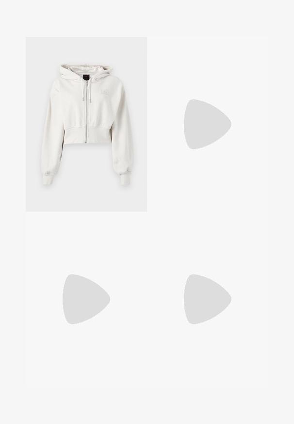 Sudadera con capucha recortada en un tono beige claro. Tejido suave, cierre delantero con cremallera, puños acanalados y logo bordado en la parte superior izquierda del pecho.; Camiseta de algodón blanca con cuello redondo y mangas cortas. Presenta un pequeño logotipo negro de Nike en el pecho. Diseño sencillo y sin adornos.; Pantalones deportivos blancos de pierna ancha con una cinturilla acanalada y un sutil detalle de logo. Tela suave con un ajuste relajado y dobladillo ajustado.; Zapatillas blancas con acentos durazno, parte superior de cuero suave, punta perforada, suela texturizada y cordones. Usadas con calcetines blancos hasta la mitad en una superficie azul.