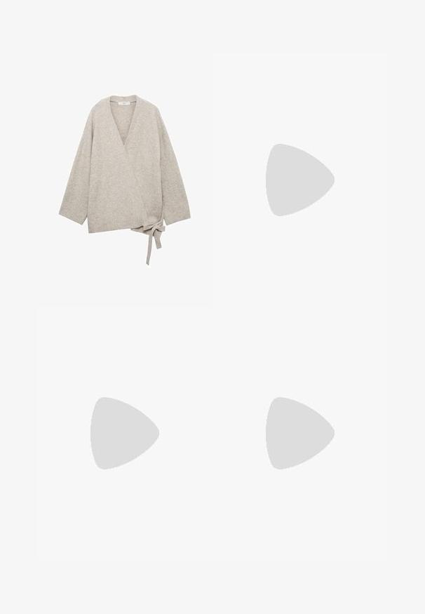 Zavojni kardigan svijetlosmeđe pletene tkanine, s širokim rukavima, V-izrezom i vezanjem u struku. Mekan, teksturiran završetak.; Bijela majica kratkih rukava od pamuka. Ima okrugli izrez i opušteni kroj. Glatka tekstura bez vidljivih uzoraka ili naglasaka.; Svijetloplave široke traperice s visokim strukom, s izbljeđenim pranjem i malim, raštrkanim oštećenjima na cijeloj površini.; Smeđe antilop čizme na platformu s kremastim krznom, u paru s širokim trapericama s rastrganim rubovima i svjetlijim traper rukavima.