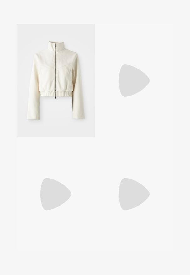 Zkrátená krémová fleecová bunda s vysokým golierom, predným zipsom, rebrovaným lemom a jemným logom na hrudi; hladká textúra a moderný dizajn.; Čierny žebrovaný športový podprsenka s výstrihom do V a širokými ramienkami. Obsahuje malé biele logo na ľavej strane. Mäkko, pružné tkanivo.; Svetlé krémové nohavice voľného strihu so stiahnutým pásom a šnúrkou, s bočnými vreckami a textúrovanou tkaninou.; Béžové športové topánky s textúrovaným zvrškom, bielymi šnúrkami a hrubou bielou podrážkou. Dizajn obsahuje jemné krivky a malé logo.