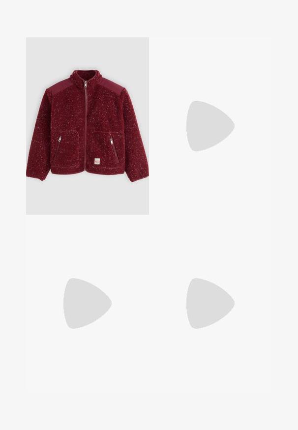 Rote Fleecejacke mit strukturierter Oberfläche, hohem Kragen, Reißverschluss und zwei Fronttaschen. Verfügt über kontrastierende Schulterpaneele.; Langarmshirt in Schwarz und roten Streifen, runder Halsausschnitt, Baumwollstoff, lockere Passform, mit geradem Saum und Seitennähten.; Beige weit geschnittene Hosen mit gefaltetem Vorderteil, Knopfverschluss und glatter Textur. Verfügt über einen taillierten Bund und seitliche Taschen.; Braune Lederloafers mit runder Zehenpartie, zwei Bändern über dem Rist und dekorativen Beschlägen in Goldton an den Seiten.; Braune Handtasche aus Leder mit einer weichen, strukturierten, fellartigen Außenseite, schlankem Design, einem kurzen Griff und einem abnehmbaren Schultergurt.