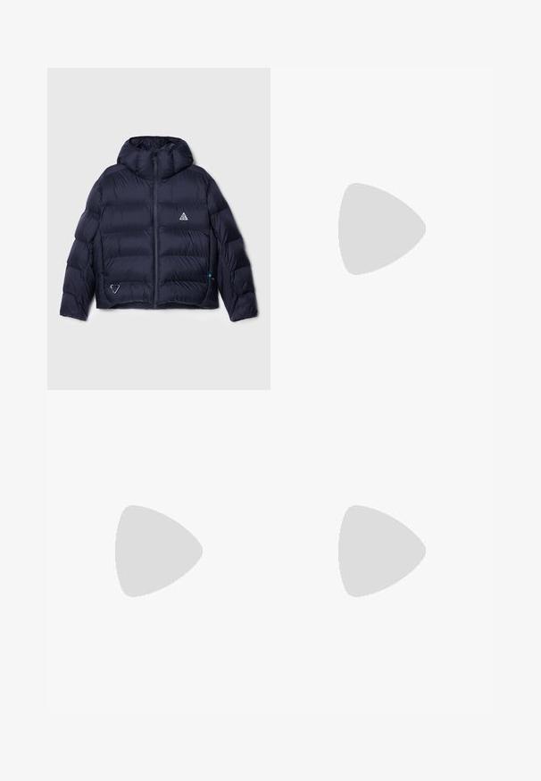 Veste rembourrée marine avec capuche, présentant un design matelassé, fermeture éclair et un logo sur la poitrine. Comprend une poche latérale avec détail en métal.; Top court en côtes de couleur bleu marine foncé, avec un col montant et un logo Nike discret. Le tissu a une apparence texturée et extensible.; Pantalons en lin beige avec une coupe décontractée, présentant des poches latérales et des détails de couture décoratifs, une taille sans coutures et des jambes droites.; Baskets marron et crème en matériaux daim et cuir, avec un bout perforé, des lacets et des semelles blanches. Portées avec un pantalon blanc.