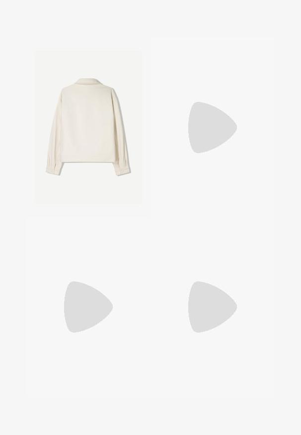 Krämfärgad jacka med strukturerad krage, långa ärmar och knappade manschetter. Tillverkad av textil med struktur, med en boxig passform och minimal detaljer.; Vit t-shirt med kort ärm som har en svartvit tryck av läppar och päron, små gående figurer och texten "GÖR KONST" under bilden.; Bruna bomullbyxor med lös passform, som har synliga sömmar, lappar och en något rynkig yta.; Bruna mocka sneakers med vit gummisula, rund tå, sex metallöglor och präglad logodetalj på sidan. Klassisk snörningsdesign.