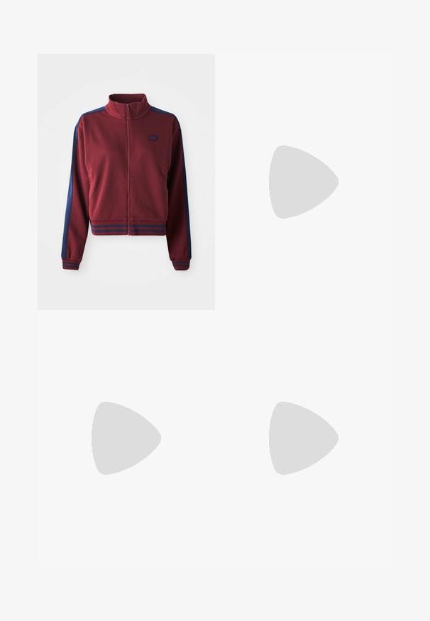 Bordeauxfarvet zip-up jakke med høj krave, marineblå sidepaneller og stribede detaljer ved manchetterne og livstykket. Blødt, tekstureret stof.; Hvid bomulds-t-shirt med en afslappet pasform, korte ærmer og et lille broderet logo på venstre brystområde.; Beige bomuldsbukser med brede ben og en glat tekstur, der har forlommer og en sølvknap i taljen.; Adidas Gazelle sneaker med en creme farvet ruskindsoverdel, blå læderdetaljer, tre blå striber, beige mellemsål og brune gummisål.