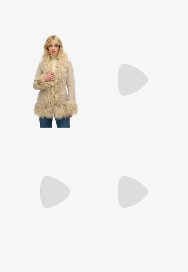 Beige jas met een getextureerde, harige nep-fur rand langs de kraag, mouwen en zoom. Glad stoffen lijf met een getailleerd ontwerp.; Twee t-shirts met korte mouwen, één wit en één zwart, gemaakt van katoen. Beide hebben een ronde halslijn en een eenvoudig, klassiek ontwerp.; Zwarte wijde jeans van denim, met kleine stippenpatronen, een klassieke vijf-pocket ontwerp en een knoop- en ritssluiting.; Zwarte slipper met twee gouden gesps, gladde textuur, platte zool en een minimalistisch ontwerp.