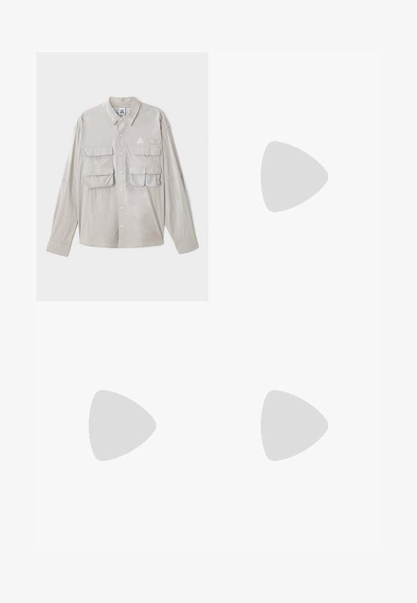 Light gray button-up shirt with long sleeves, four front pockets, a triangular logo, and a smooth fabric texture.; White short-sleeve t-shirt in cotton blend with round neck, featuring graphic text "FRIENDS WITH TREES" and hexagon design on the left chest.; Black, elasticated-waist sweatpants with a loose fit, cuffed ankles, smooth texture, and no visible patterns or hardware accents.; Black low-top sneakers with white laces and stitching, paired with loose beige cargo pants, standing on blue carpet.