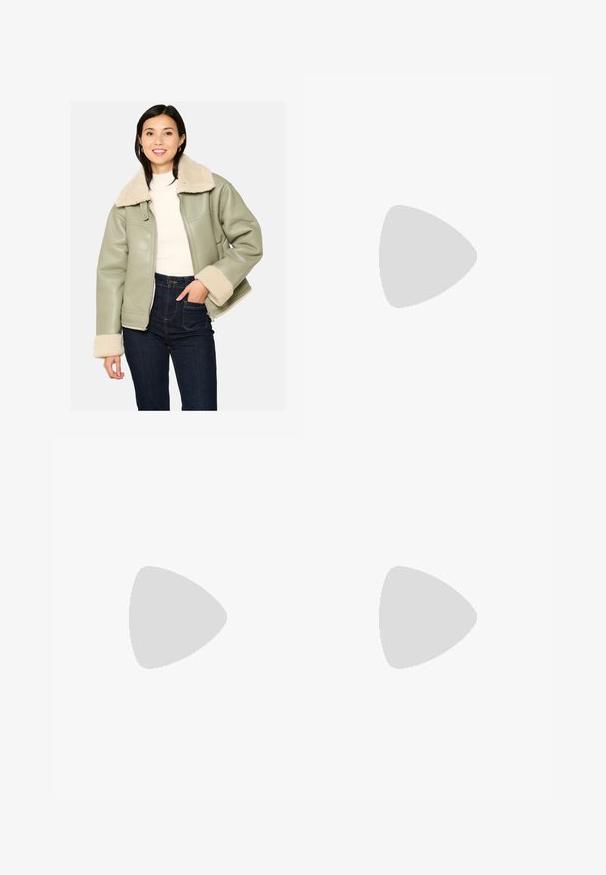 Giacca in ecopelle verde con colletto e polsini in shearling crema, dotata di tasche laterali e chiusura con zip. Indossata con jeans a vita alta.; T-shirt bianca in cotone con collo rotondo classico, maniche corte e forma aderente. Nessun motivo o dettaglio visibile.; Pantaloni tuta grigi con vita elastica, dettaglio con cordino e piccolo logo Nike bianco sulla coscia sinistra. Tessuto morbido, vestibilità ampia.; Sneaker bianchi in pelle con accenti grigi, punta perforata, lacci piatti, collo imbottito e suola in gomma testurizzata.
