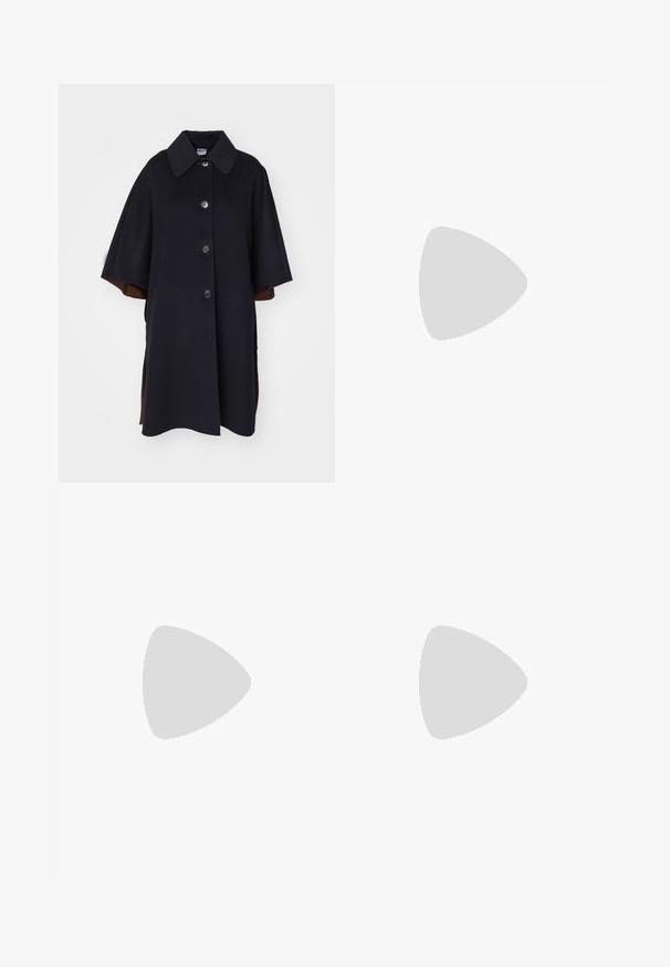 Cappotto in misto lana nero con ampio colletto, dotato di chiusura frontale a bottoni e maniche corte. Le fessure laterali rivelano un rivestimento marrone.; Camicia a maniche lunghe di colore crema con scollatura rotonda. Presenta righe verticali e un design aderente. Realizzata in un morbido tessuto a maglia.; Pantaloni neri a gamba larga realizzati in un tessuto morbido, con vita alta, pieghe e un design sartoriale. Finiture semplici in nero in vita.; Scarpe sportive con tomaia in pelle bianca, punta in suede grigia e tre strisce nere. Presentano un logo blu sulla linguetta e una suola in gomma testurizzata.